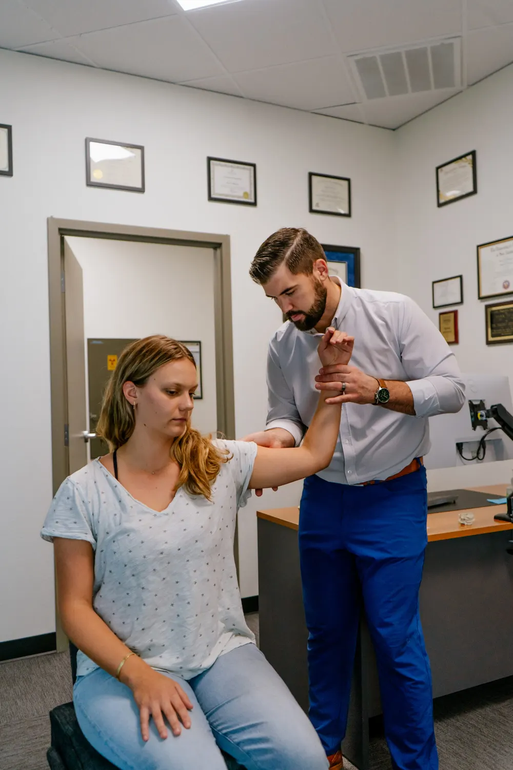 Chiropractor treating a seated patient's arm pain