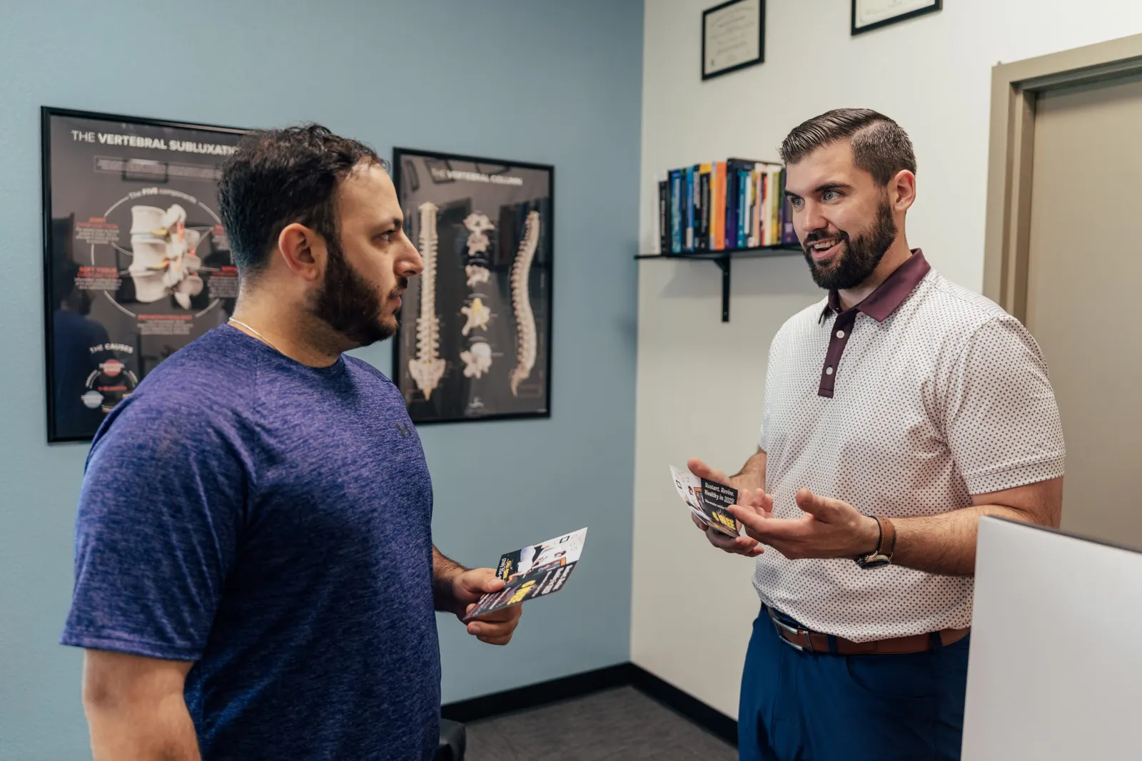 Dr. Brent Johnson talking with a patient in front of spine model posters