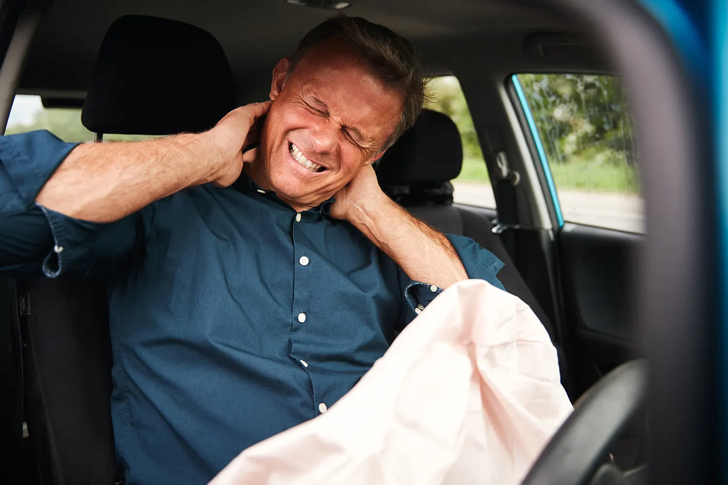 a man suffering from a whiplash inside his car